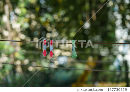 Multi-colored plastic clothespins on a stretched clothesline against a blurred autumn background 137730859