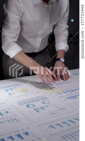 Professional businessman analyzing financial data and charts on laptop and paper documents, writing notes late at night, working overtime in modern office researching company growth and strategy Professional businessman analyzing financial data and charts on laptop and paper documents, writing notes late at night, working overtime in modern office researching company growth and strategy 137731448