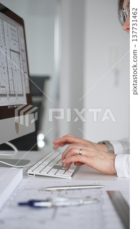 Architect working on building blueprint plans, designing new projects with computer and drawing tools. Business and architecture concept Architect working on building blueprint plans, designing new projects with computer and drawing tools. Business and architecture concept 137731462