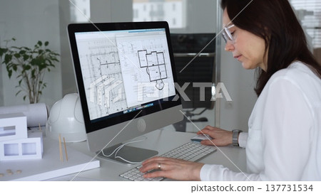 Woman architect drawing building plans on computer, designing modern housing project with cad software. Business and architecture concept Woman architect drawing building plans on computer, designing modern housing project with cad software. Business and architecture concept 137731534