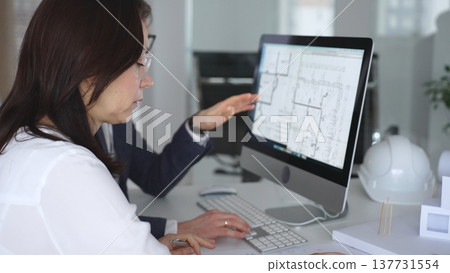 Architects collaborating on building plans using computer aided design software and architectural models. Business and architecture concept Architects collaborating on building plans using computer aided design software and architectural models. Business and architecture concept 137731554