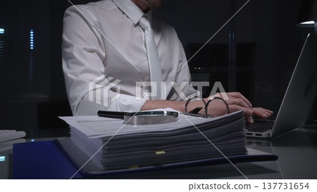 Businessman analyzing financial documents and paperwork at desk, working overtime in a dark office, researching data for investigation. Audit and taxes in business Businessman analyzing financial documents and paperwork at desk, working overtime in a dark office, researching data for investigation. Audit and taxes in business 137731654