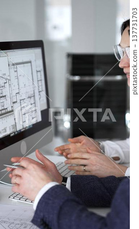 Architects and engineers collaborating on a project, analyzing construction blueprints with drafting tools during client meeting. Business people and architecture concept Architects and engineers collaborating on a project, analyzing construction blueprints with drafting tools during client meeting. Business people and architecture concept 137731703