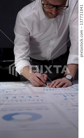 Professional businessman working late nights in office, analyzing financial data and statistics, managing overwork and project deadlines to achieve business success and productivity Professional businessman working late nights in office, analyzing financial data and statistics, managing overwork and project deadlines to achieve business success and productivity 137731841