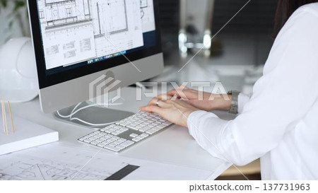 Architect working at desktop computer, checking blueprints and design plans for a new engineering project. Business and architecture concept Architect working at desktop computer, checking blueprints and design plans for a new engineering project. Business and architecture concept 137731963