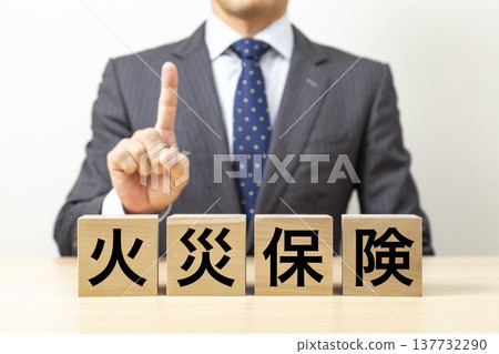 A block with "Fire Insurance" written on it and a businessman A block with "Fire Insurance" written on it and a businessman 137732290