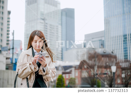 一位女商人在城市裡使用智慧型手機 137732313