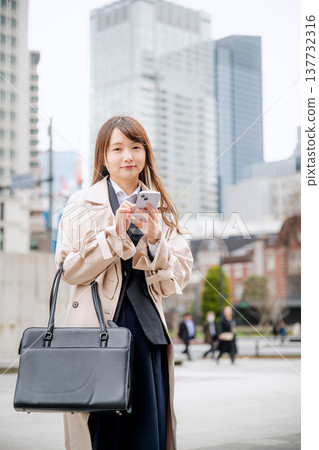 一位女商人在城市裡使用智慧型手機 一位女商人在城市裡使用智慧型手機 137732316