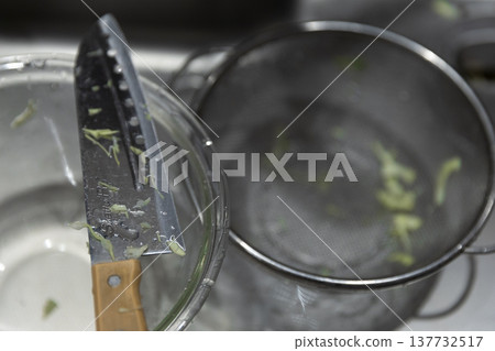 濾鍋裡剩下的切絲高麗菜;洗碗;碗和刀。 濾鍋裡剩下的切絲高麗菜;洗碗;碗和刀。 137732517