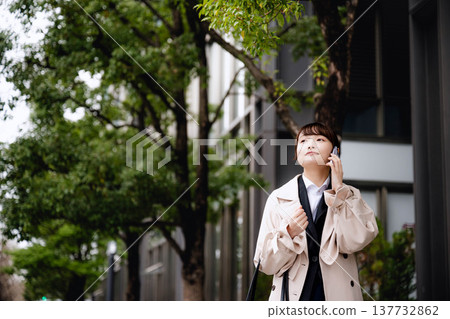 一位年輕的女商人正在辦公區打電話。 一位年輕的女商人正在辦公區打電話。 137732862