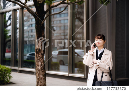 一位年輕的女商人正在辦公區打電話。 一位年輕的女商人正在辦公區打電話。 137732870