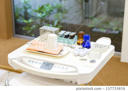 A clean dental clinic with a pristine examination chair and medical equipment; a bright treatment room with a view of the courtyard greenery. A clean dental clinic with a pristine examination chair and medical equipment; a bright treatment room with a view of the courtyard greenery. 137733659