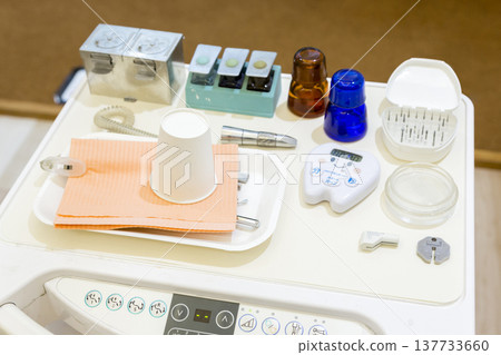 Medical instruments and cups lined up on a dental chair: an image of dental treatment preparation and oral care. 137733660