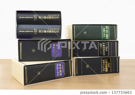 A pile of professional books and legal codes for certified social insurance and labor consultants: an image of labor management and compliance with legal revisions. A pile of professional books and legal codes for certified social insurance and labor consultants: an image of labor management and compliance with legal revisions. 137733663