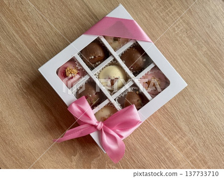 Delicious, sweet handmade chocolates made of white and milk chocolate with whole nuts in a gift box on a light background. High quality photo Delicious, sweet handmade chocolates made of white and milk chocolate with whole nuts in a gift box on a light background. High quality photo 137733710