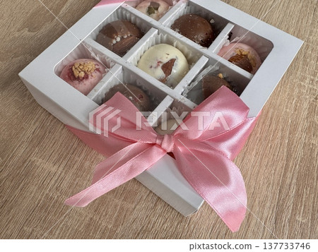Delicious, sweet handmade chocolates made of white and milk chocolate with whole nuts in a gift box on a light background. High quality photo Delicious, sweet handmade chocolates made of white and milk chocolate with whole nuts in a gift box on a light background. High quality photo 137733746