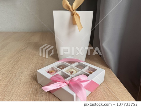 Delicious, sweet handmade chocolates made of white and milk chocolate with whole nuts in a gift box on a light background. High quality photo Delicious, sweet handmade chocolates made of white and milk chocolate with whole nuts in a gift box on a light background. High quality photo 137733752