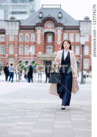 A businesswoman in a suit walking in front of Tokyo Station. A businesswoman in a suit walking in front of Tokyo Station. 137734270