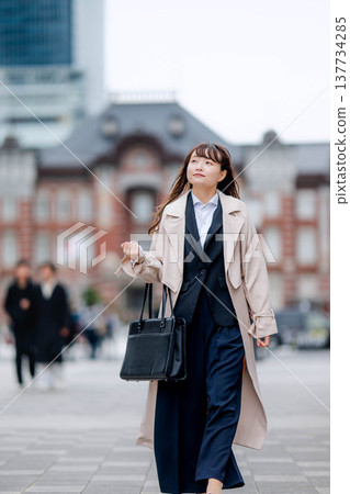 一位身穿職業套裝的女商人走在東京車站前。 一位身穿職業套裝的女商人走在東京車站前。 137734285