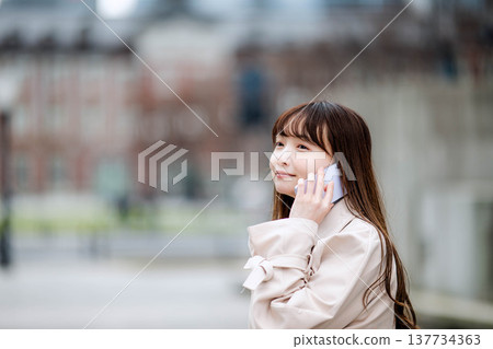 一位女商人外出時正在打電話。 137734363