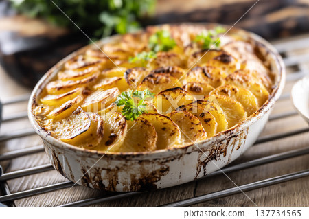 Golden-brown gratin potatoes, neatly arranged in a white ceramic bowl and garnished with fresh herbs. In Slovakia, however, this dish is known primarily at home as French potatoes Golden-brown gratin potatoes, neatly arranged in a white ceramic bowl and garnished with fresh herbs. In Slovakia, however, this dish is known primarily at home as French potatoes 137734565