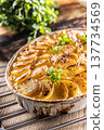 Golden-brown gratin potatoes, neatly arranged in a white ceramic bowl and garnished with fresh herbs. In Slovakia, however, this dish is known primarily at home as French potatoes 137734569
