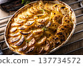 Golden-brown gratin potatoes, neatly arranged in a white ceramic bowl and garnished with fresh herbs. In Slovakia, however, this dish is known primarily at home as French potatoes 137734572