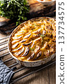Golden-brown gratin potatoes, neatly arranged in a white ceramic bowl and garnished with fresh herbs. In Slovakia, however, this dish is known primarily at home as French potatoes 137734575