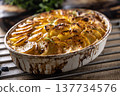 Golden-brown gratin potatoes, neatly arranged in a white ceramic bowl and garnished with fresh herbs. In Slovakia, however, this dish is known primarily at home as French potatoes 137734576
