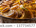 Golden-brown gratin potatoes, neatly arranged in a white ceramic bowl and garnished with fresh herbs. In Slovakia, however, this dish is known primarily at home as French potatoes 137734577