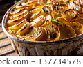 Golden-brown gratin potatoes, neatly arranged in a white ceramic bowl and garnished with fresh herbs. In Slovakia, however, this dish is known primarily at home as French potatoes 137734578