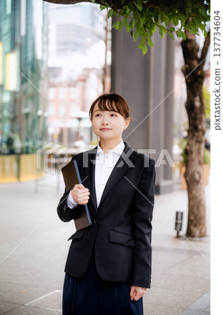 一位年輕女子將筆記型電腦抱在胸前。 137734604