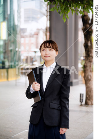 一位年輕女子將筆記型電腦抱在胸前。 137734605