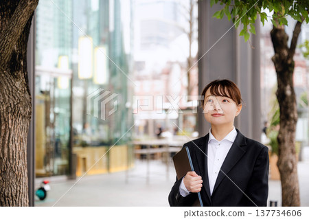 一位年輕女子將筆記型電腦抱在胸前。 137734606