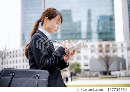 一位女商人坐在長椅上查看她的日程安排。 一位女商人坐在長椅上查看她的日程安排。 137734784