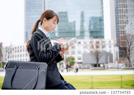 一位女商人坐在長椅上查看她的日程安排。 一位女商人坐在長椅上查看她的日程安排。 137734785