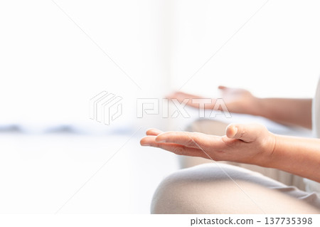 Close-up of hands in yoga meditation mudra during mindfulness practice, soft bright background with copy space. Calm wellness concept for relaxation, breathing, zen and mental health. 137735398