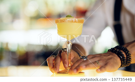 Bartender preparing a yellow cocktail on a bar counter 137735449