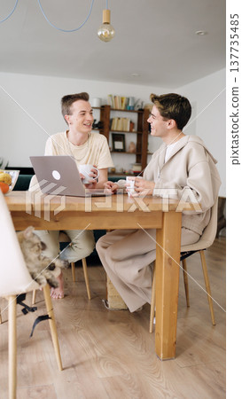 Gay couple talking together at home using laptop 137735485