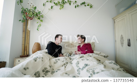 Gay couple laughing in bed enjoying morning together Gay couple laughing in bed enjoying morning together 137735540
