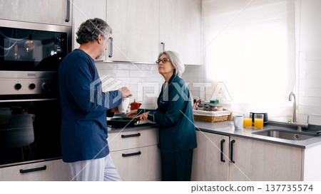 Senior couple cooking breakfast together in morning kitchen Senior couple cooking breakfast together in morning kitchen 137735574