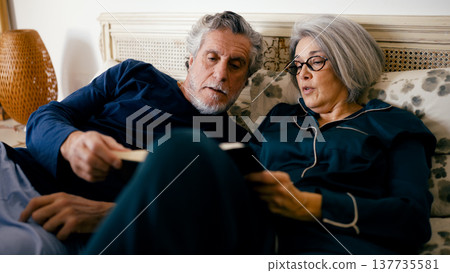 Senior couple sharing book in bed relaxing at home 137735581
