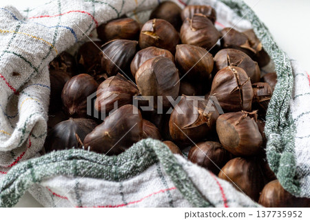 A pile of hot roasted chestnuts wrapped in a towel 137735952