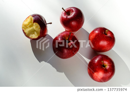 Five red ripe apples lying on a white table and their shadows Five red ripe apples lying on a white table and their shadows 137735974