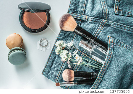 Makeup and cosmetics in jeans pocket on white table Makeup and cosmetics in jeans pocket on white table 137735995
