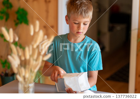 Boy weighing sugar from a pack on a kitchen scale Boy weighing sugar from a pack on a kitchen scale 137736022