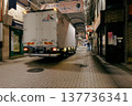 Nighttime deliveries in a shopping arcade: Light trails from moving trucks. 137736341