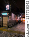 Late at night, subway station entrances and exits; deserted sidewalks and illuminated signs. 137736342