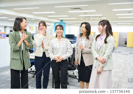 一群女員工在燈光明亮的辦公室聊天交流。 一群女員工在燈光明亮的辦公室聊天交流。 137736349