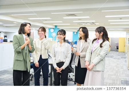 一群女員工在燈光明亮的辦公室聊天交流。 一群女員工在燈光明亮的辦公室聊天交流。 137736354
